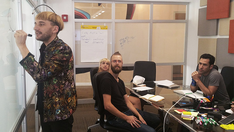 Neil drawing on a whiteboard as team members look on