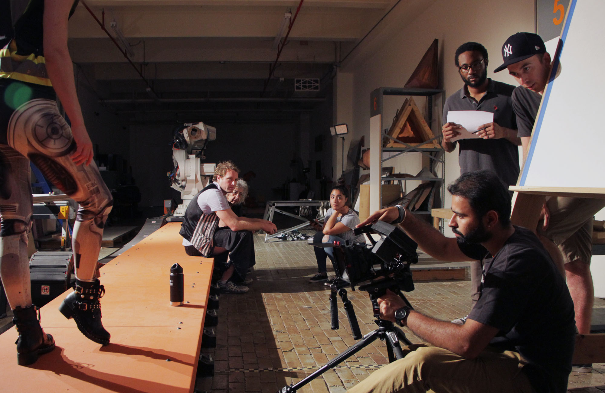 Film crew setting up between shots in a robotics lab